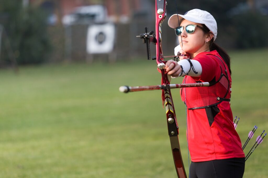 Portrait of female athlete practicing archery in stadium.