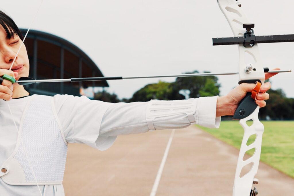 Woman, archery and target at field with sport for shooting practice and training as athlete in Japa.
