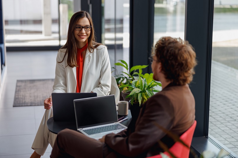 An engaging professional discussion is taking place between two colleagues in a stylish and modern office setting