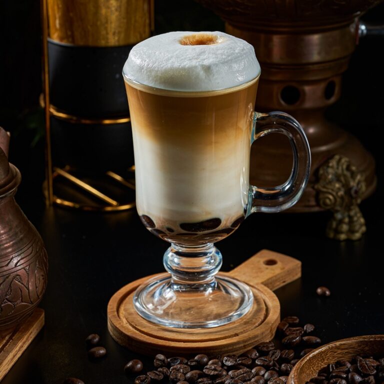 A cup of latte coffee with milk on a dark background and wooden floor
