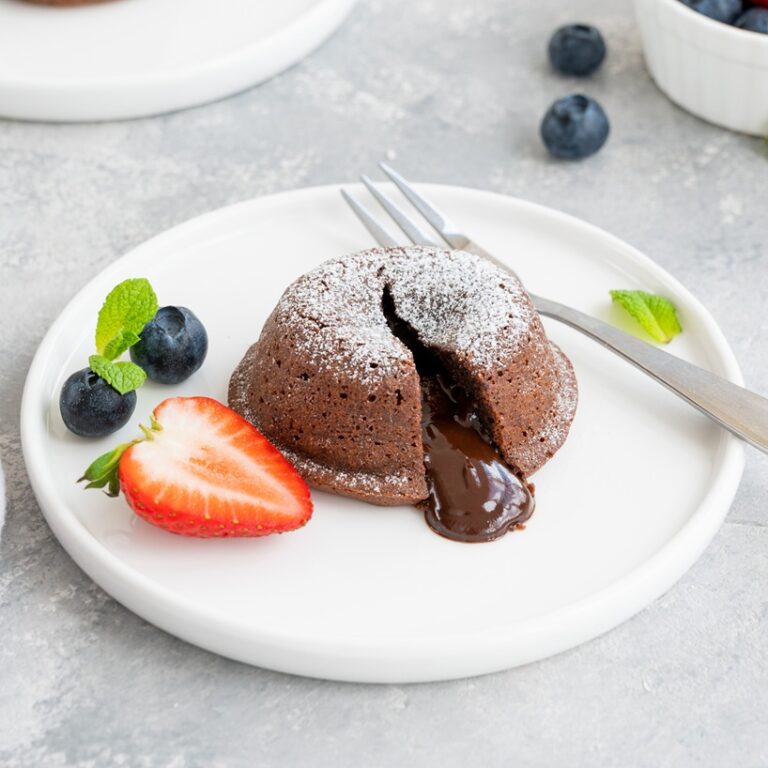 Chocolate fondant lava cake with fresh berries on a plate on a gray background