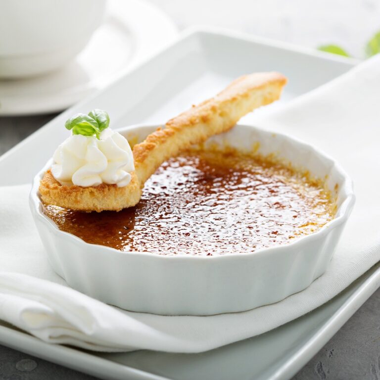 Creme brulee dessert in a white ramekin with a cup of cappuccino