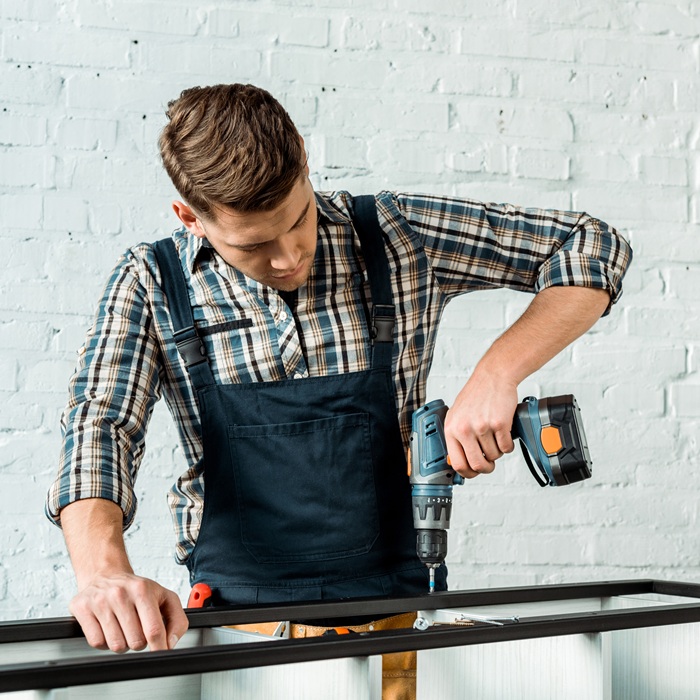 focused installer holding hammer drill near rack