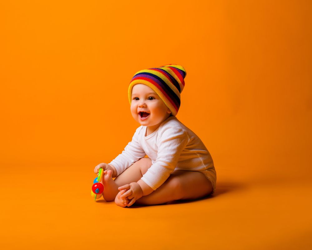 happy-infant-playing-with-colorful-toy-on-orange-b-2026-03-26-06-04-21-utc