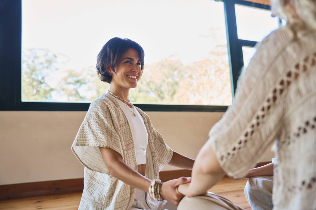 happy-yoga-coach-holding-hands-of-woman-during-gro-2026-01-08-00-17-08-utc