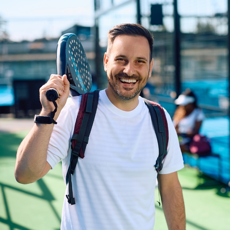 Happy athlete coming to paddle tennis exercise class and looking at camera. Copy space.