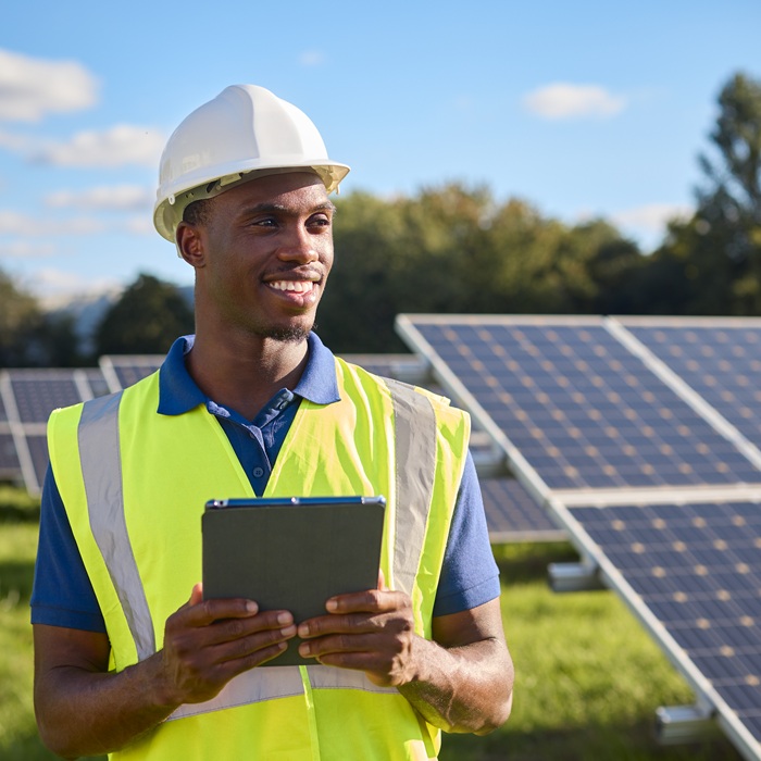 Portrait Of Male Engineer With Digital Tablet Inspecting Solar Panels Generating Renewable Energy